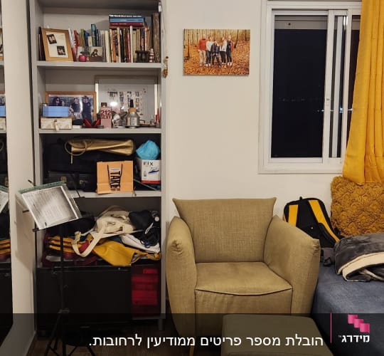 מדף עם ספרים ותמונות, כורסה ירוקה, חלון עם וילון צהוב